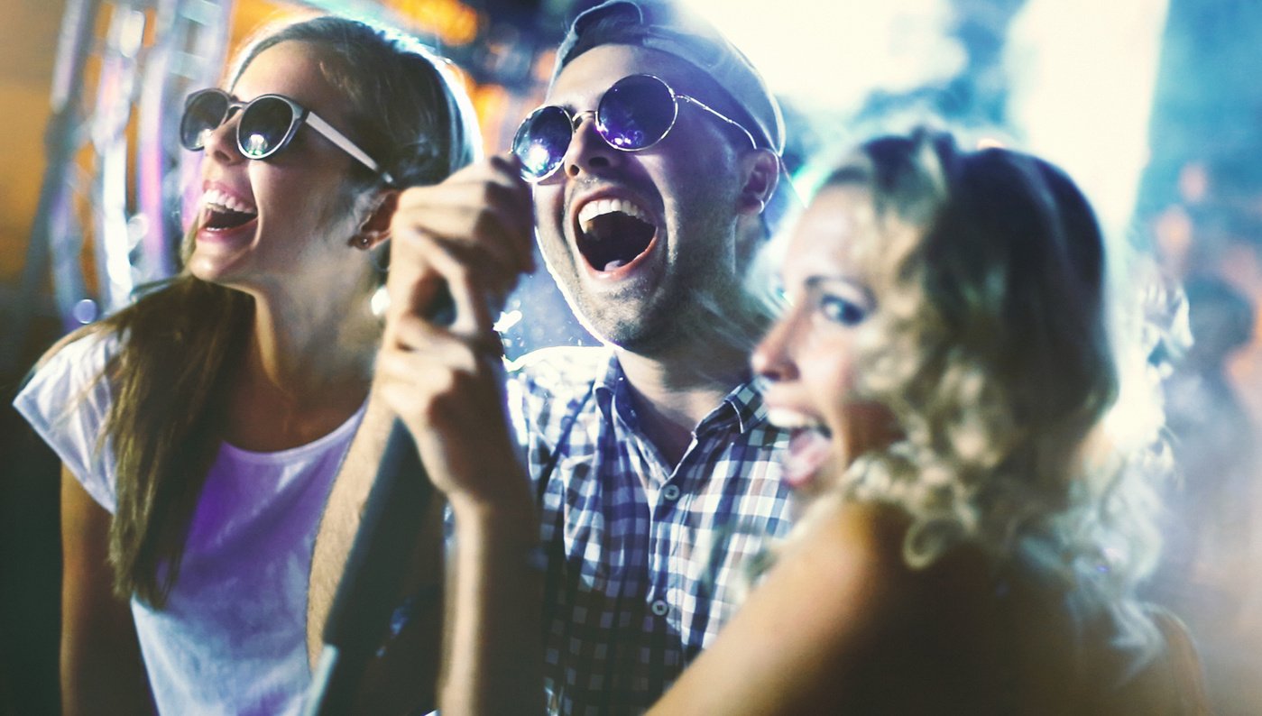 a group of people having fun at a party. friends singing along to their favorite songs in the car with a karaoke machine set up on the dashboard, creating a fun and lively atmosphere during their road trip