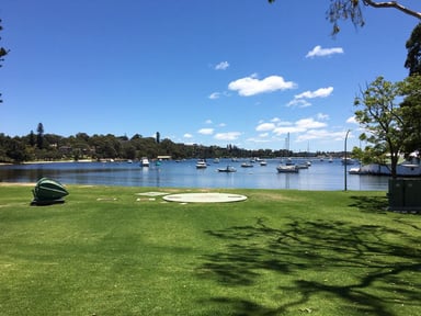 a green lawn with boats in swan river , perth, australia